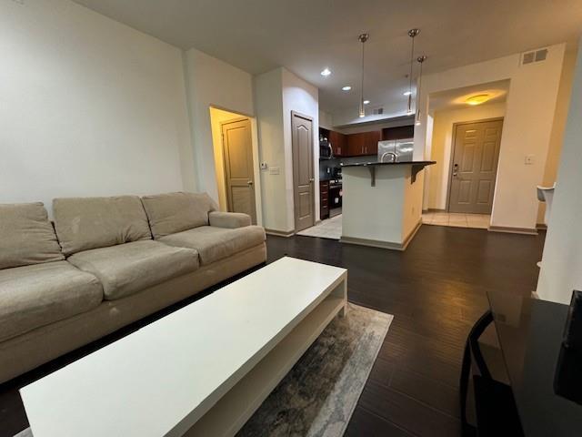 living area featuring visible vents, recessed lighting, and dark wood-style flooring