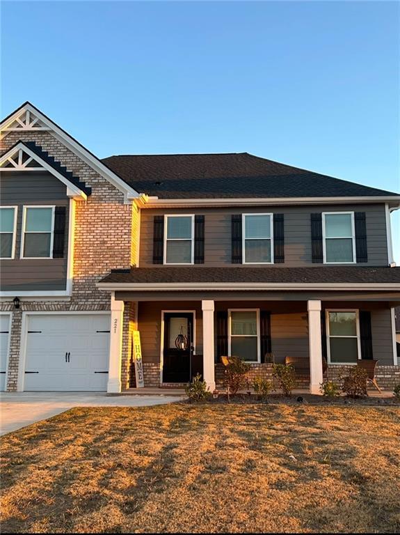 view of front of home featuring a garage, covered porch, and a front lawn