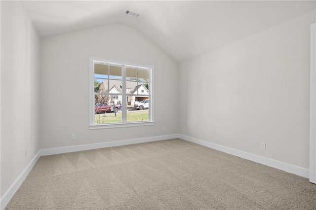 spare room featuring light carpet and lofted ceiling