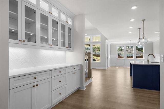 kitchen featuring white cabinets, decorative backsplash, pendant lighting, and sink