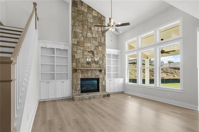 unfurnished living room with built in shelves, a fireplace, high vaulted ceiling, and light hardwood / wood-style floors