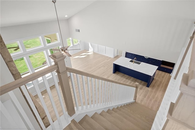 staircase with hardwood / wood-style flooring, ceiling fan, and high vaulted ceiling