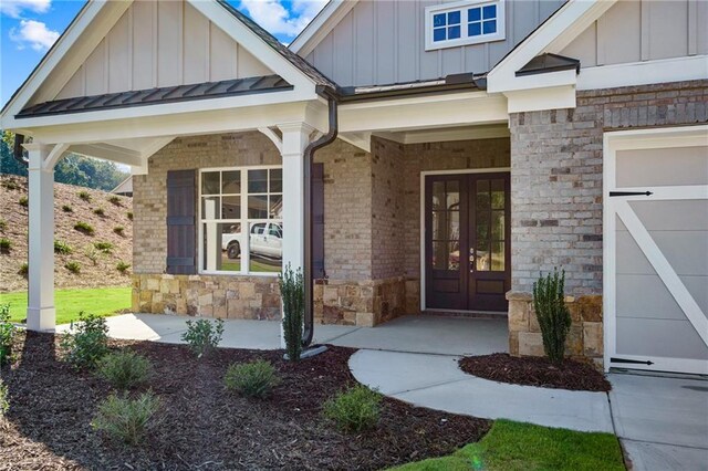 view of exterior entry with french doors, a porch, and a garage