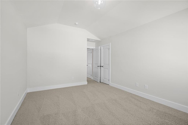 spare room with light colored carpet and vaulted ceiling