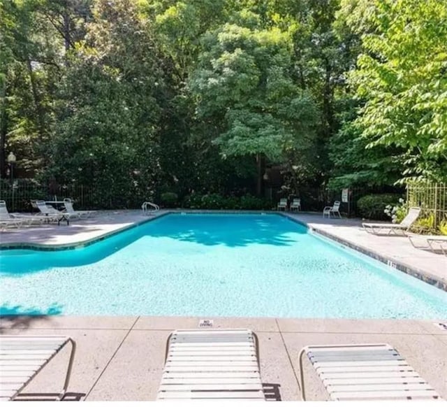 community pool featuring fence and a patio area
