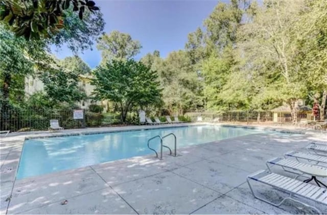 community pool with fence and a patio area
