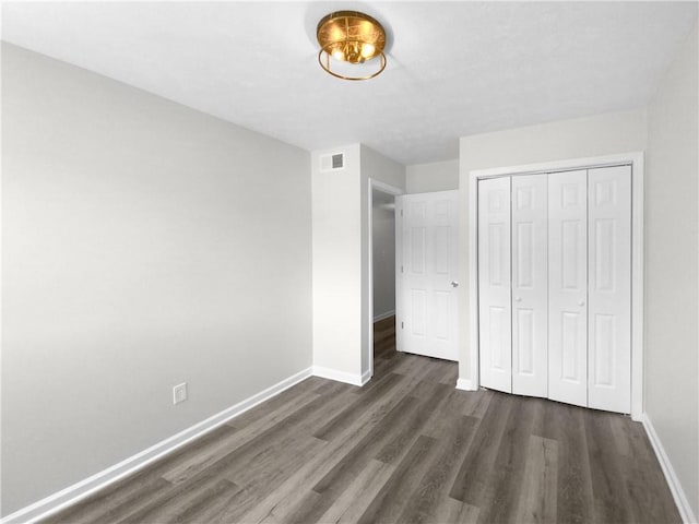 unfurnished bedroom with a closet and dark hardwood / wood-style flooring