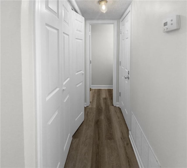 corridor with dark wood-type flooring and a textured ceiling