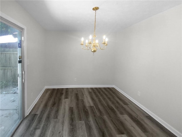 spare room with dark hardwood / wood-style floors and an inviting chandelier