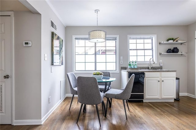 dining room featuring sink, ornamental molding, and hardwood / wood-style floors