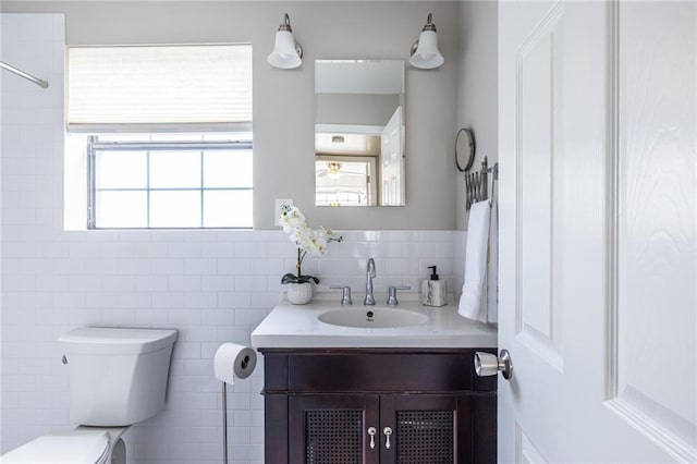 bathroom with vanity, plenty of natural light, tile walls, and toilet