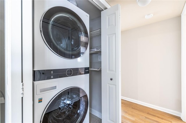 laundry area with hardwood / wood-style flooring and stacked washer and clothes dryer