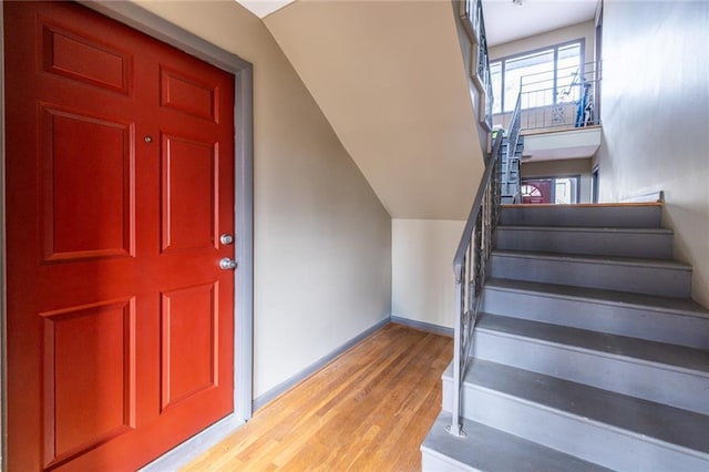 stairs with wood-type flooring and vaulted ceiling