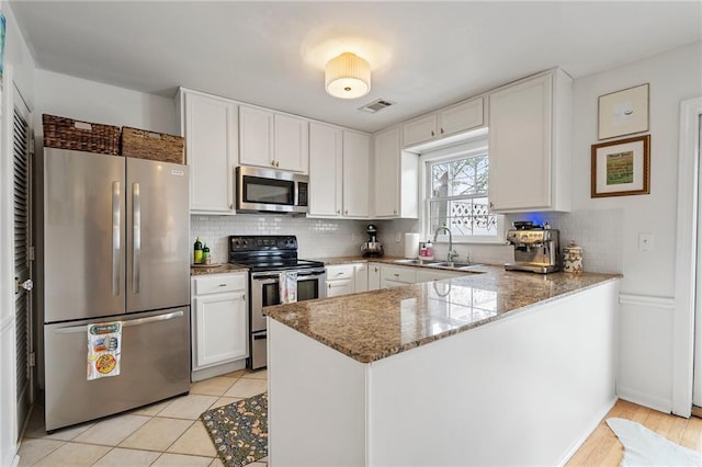 kitchen featuring visible vents, white cabinets, appliances with stainless steel finishes, a peninsula, and stone counters