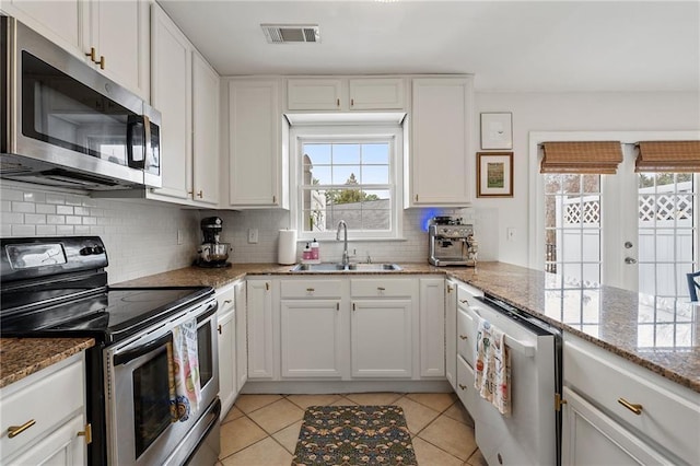 kitchen with a sink, visible vents, white cabinets, appliances with stainless steel finishes, and tasteful backsplash