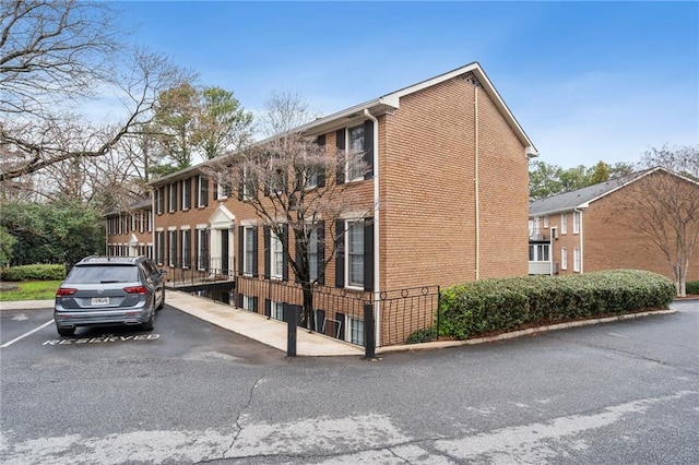 view of side of property with uncovered parking and brick siding