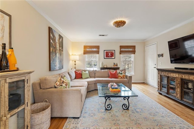 living room featuring baseboards, visible vents, wood finished floors, and ornamental molding