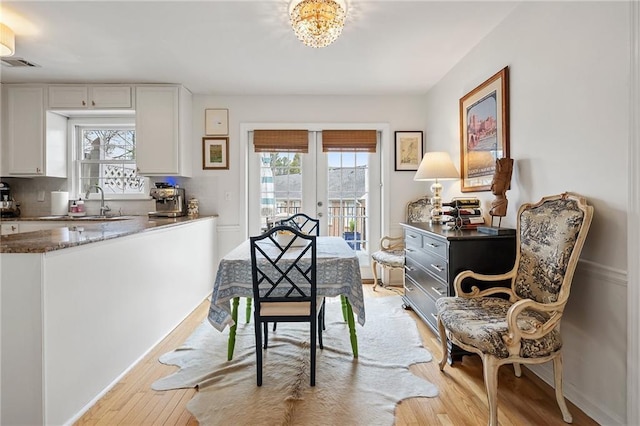 dining room featuring french doors, light wood-style flooring, visible vents, and baseboards