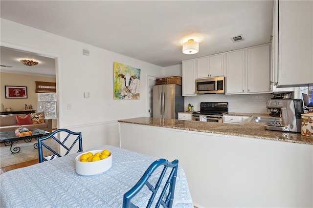 kitchen featuring visible vents, white cabinets, wood finished floors, light stone countertops, and stainless steel appliances