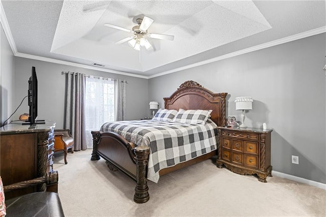 bedroom with a textured ceiling, light colored carpet, visible vents, ornamental molding, and a tray ceiling