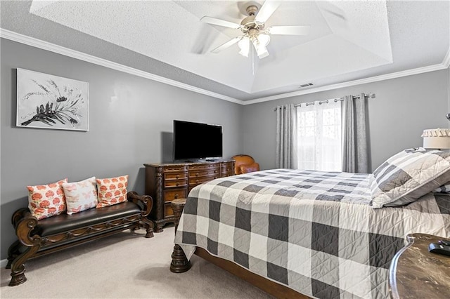 bedroom with carpet flooring, visible vents, a ceiling fan, ornamental molding, and a tray ceiling