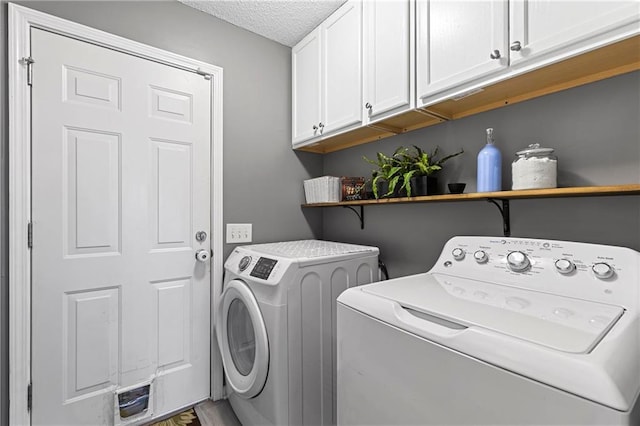 washroom with cabinet space, independent washer and dryer, and a textured ceiling