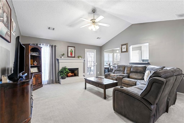 living room featuring a brick fireplace, visible vents, vaulted ceiling, and light colored carpet