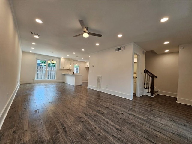 unfurnished living room featuring dark hardwood / wood-style floors, ornamental molding, and ceiling fan