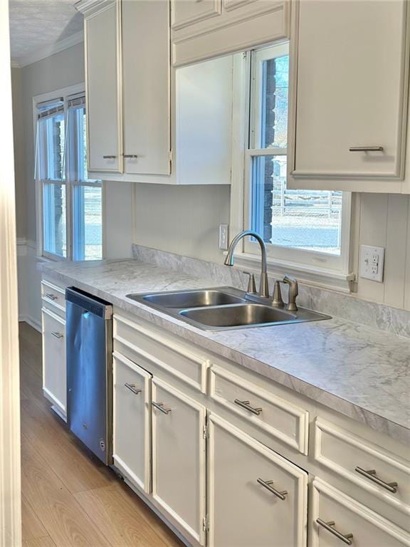 kitchen featuring white cabinetry, stainless steel dishwasher, sink, light hardwood / wood-style flooring, and ornamental molding