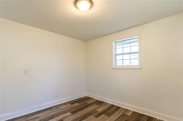 spare room with dark wood-style flooring and baseboards