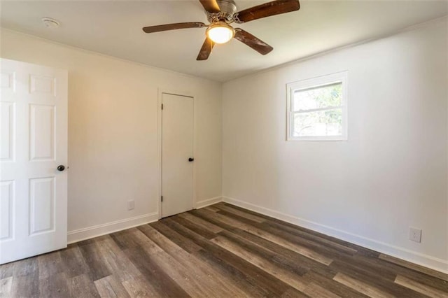 unfurnished room featuring dark wood-style flooring, a ceiling fan, and baseboards