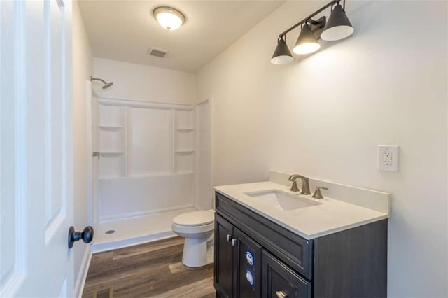 full bathroom featuring toilet, wood finished floors, vanity, visible vents, and walk in shower