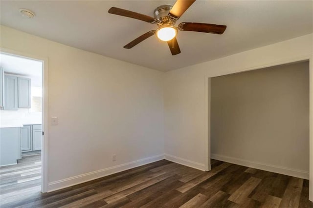 spare room with ceiling fan, baseboards, and dark wood finished floors