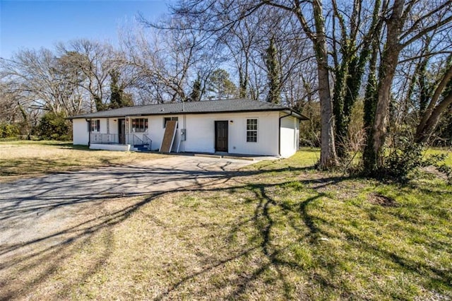 view of front of house featuring a porch, dirt driveway, and a front lawn