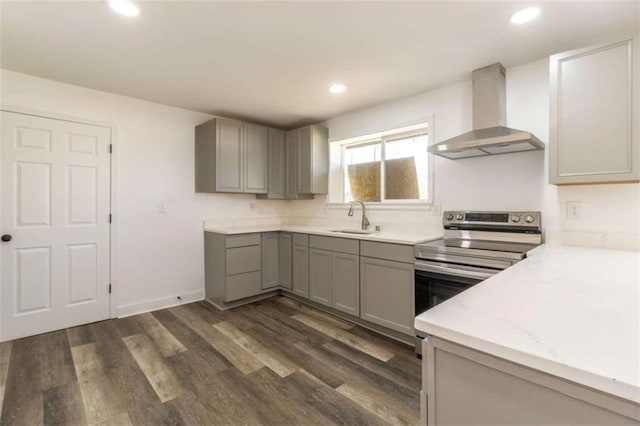 kitchen featuring wall chimney exhaust hood, dark wood-type flooring, stainless steel electric range, gray cabinets, and a sink