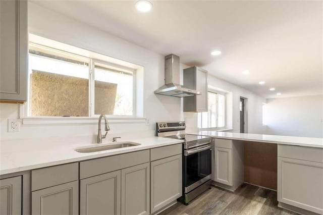 kitchen with stainless steel electric stove, recessed lighting, gray cabinets, a sink, and wall chimney exhaust hood