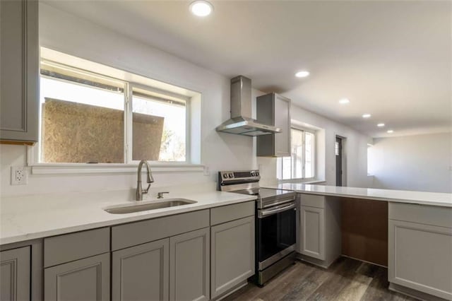 kitchen with stainless steel range with electric stovetop, gray cabinets, a sink, and wall chimney range hood