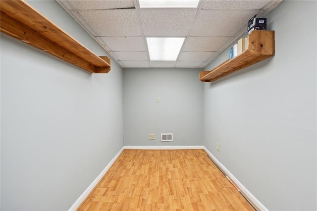 basement featuring a paneled ceiling and light hardwood / wood-style floors