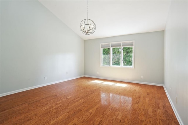 unfurnished room with wood-type flooring, vaulted ceiling, and a notable chandelier