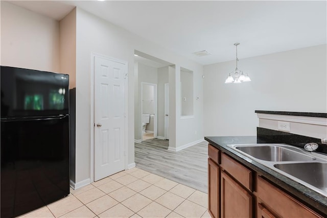 kitchen featuring freestanding refrigerator, a chandelier, dark countertops, light tile patterned flooring, and decorative light fixtures