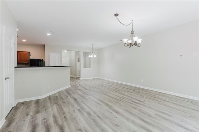 unfurnished living room with a chandelier, light wood-type flooring, recessed lighting, and baseboards