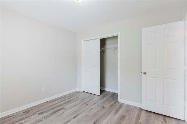 unfurnished bedroom with light wood finished floors, a closet, and baseboards