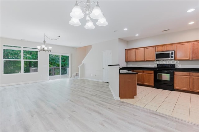kitchen featuring black / electric stove, stainless steel microwave, a chandelier, dark countertops, and brown cabinets