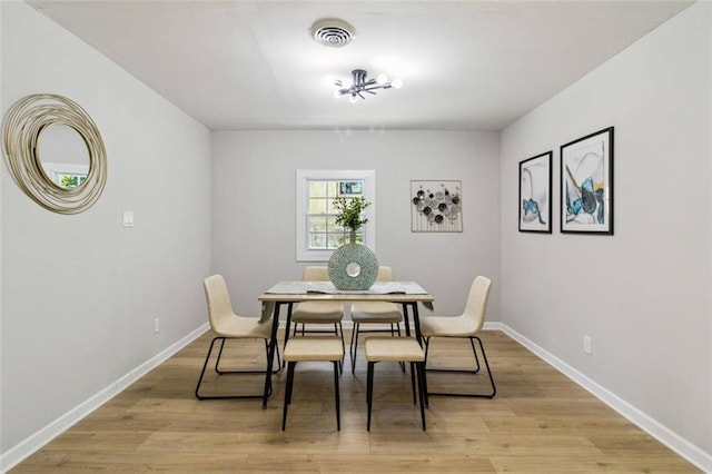 dining area with light wood-style floors, visible vents, and baseboards