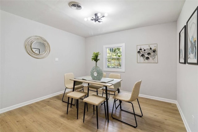 dining area with light wood-style flooring, an inviting chandelier, visible vents, and baseboards