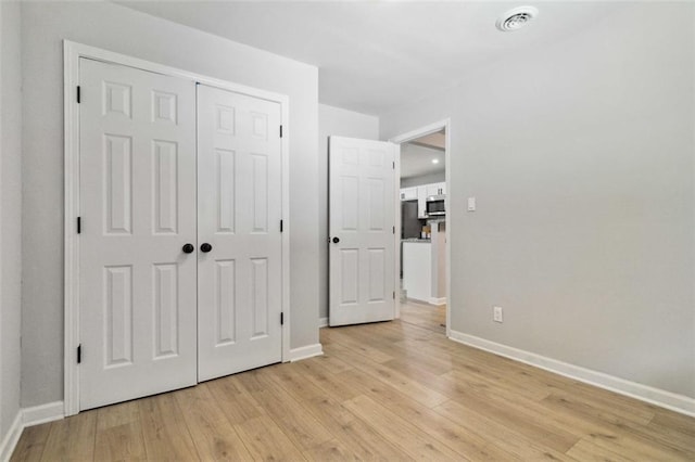 unfurnished bedroom featuring a closet, light wood-style flooring, and baseboards