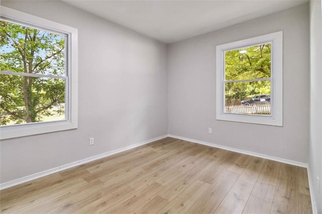 empty room featuring light wood finished floors, plenty of natural light, and baseboards