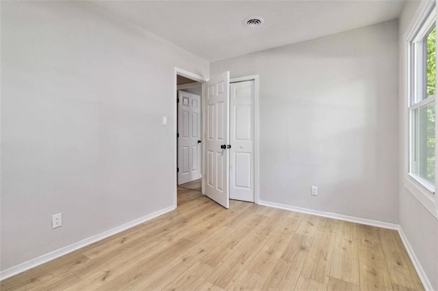 empty room with a healthy amount of sunlight, light wood-style floors, and baseboards