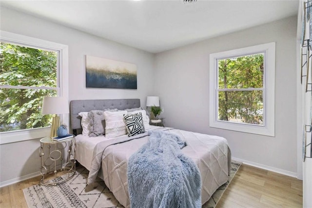 bedroom with light wood-style floors and multiple windows