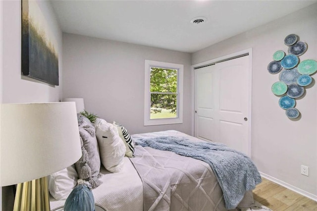 bedroom featuring a closet, wood finished floors, visible vents, and baseboards